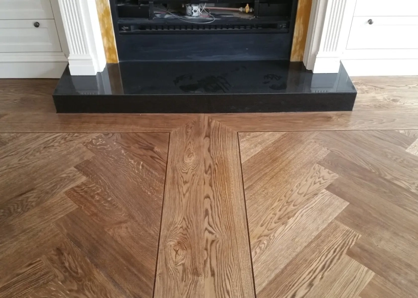 European Oak Herringbone Parquetry Flooring with a quadrant border design. With a Stained Waterbased Coating. Satin in sheen - Fireplace
